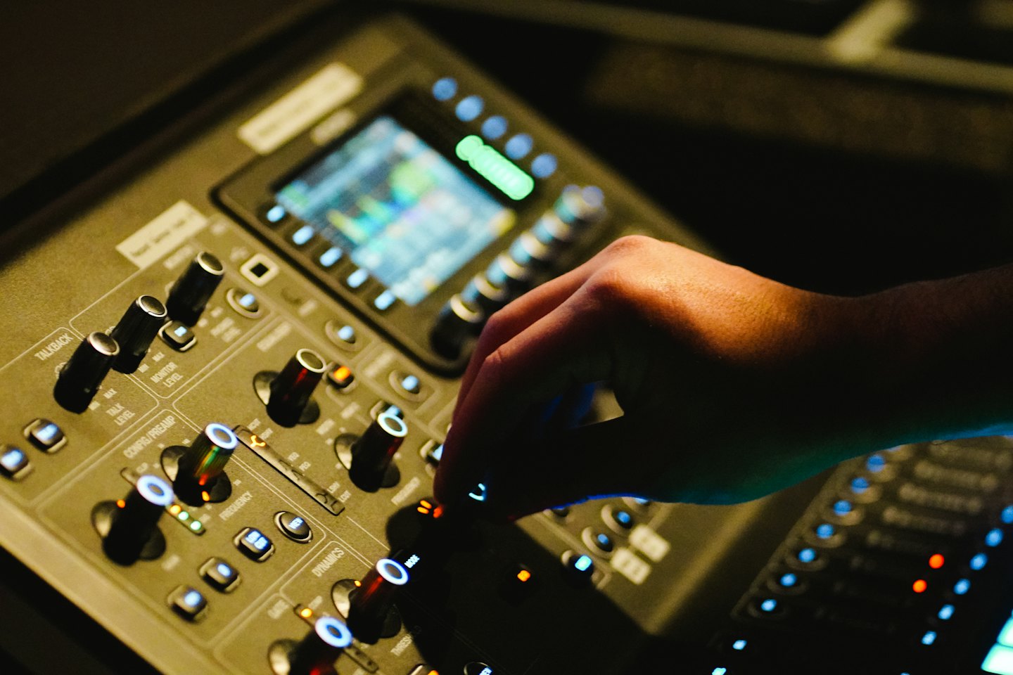 Eine Hand stellt einen Knopf an einem professionellen Audio-Mischpult ein.