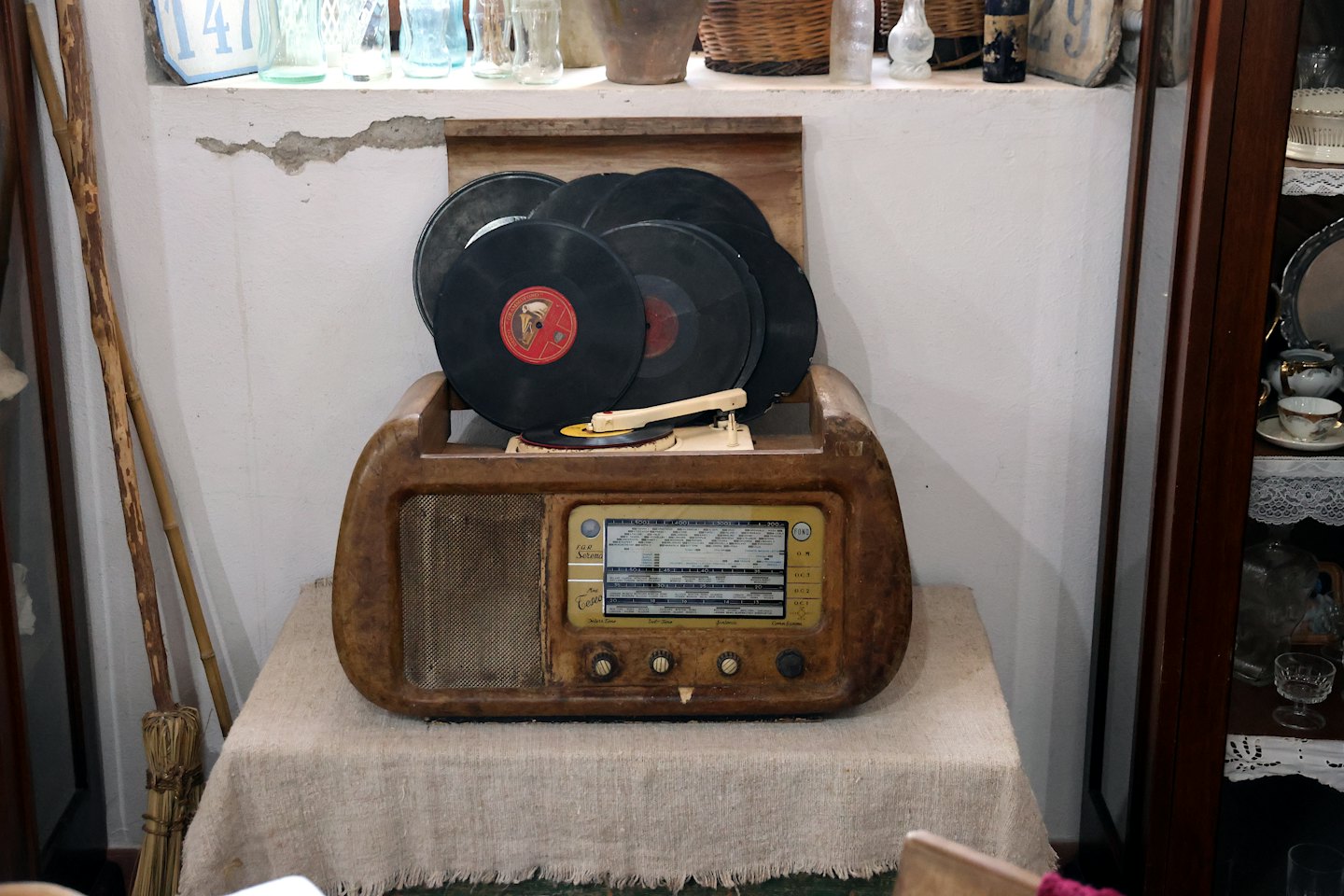 Antiker Plattenspieler mit Schallplatten auf einer Leinentischdecke.