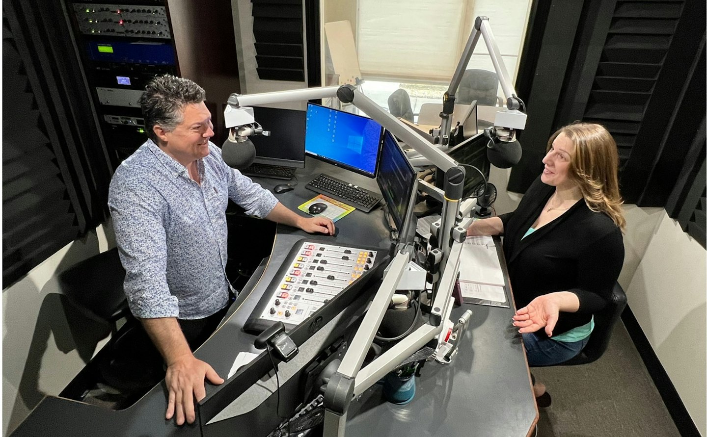 Zwei Personen besprechen ein Projekt in einem professionellen Radiostudio.