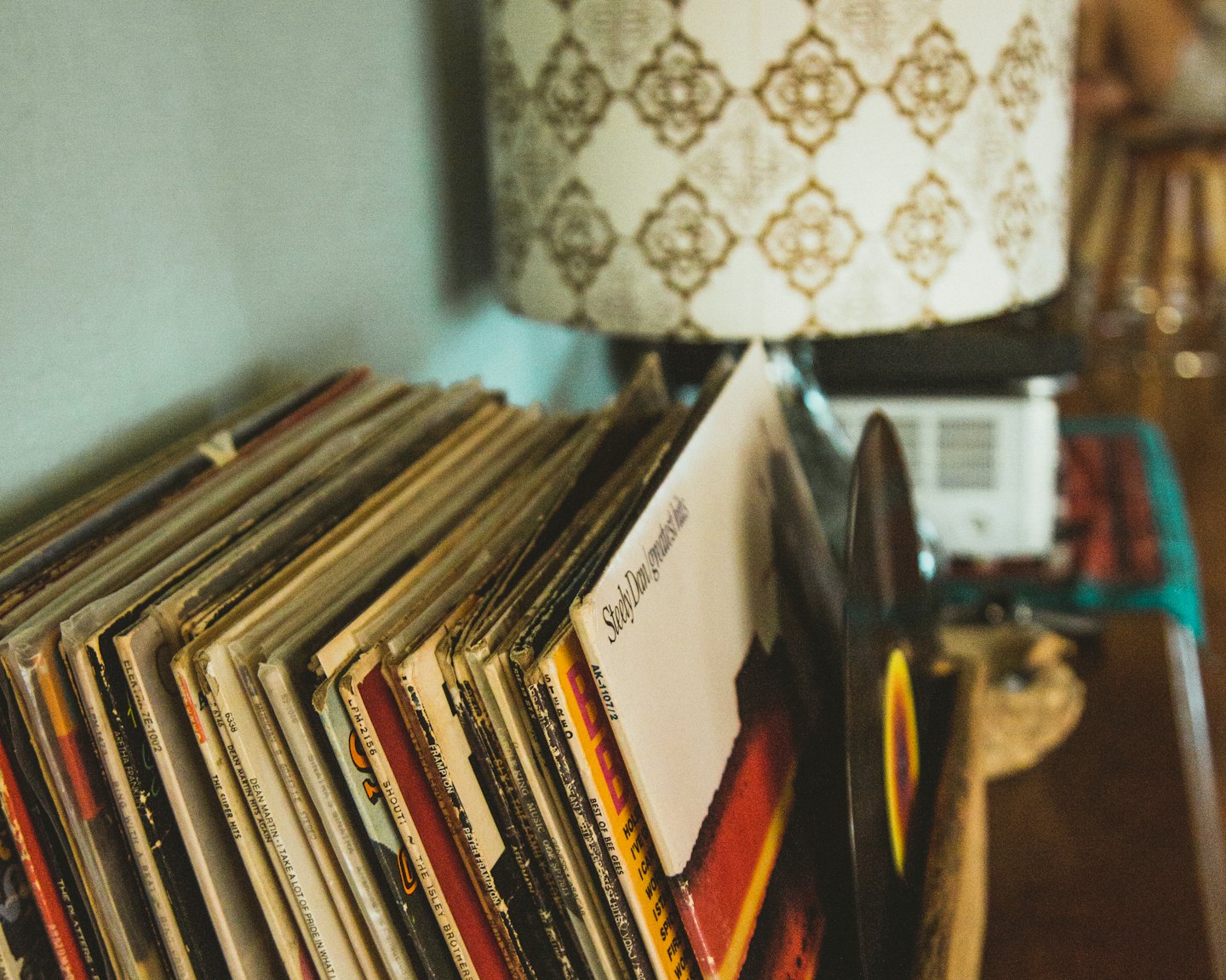 Stapel alter Schallplatten drinnen neben einer Lampe.